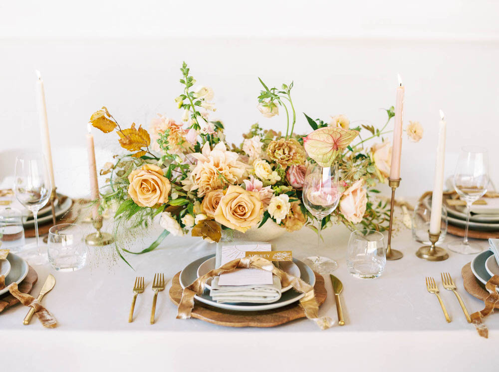 massive rose-filled centerpiece with wooden chargers and velvet bows at each pacesetting