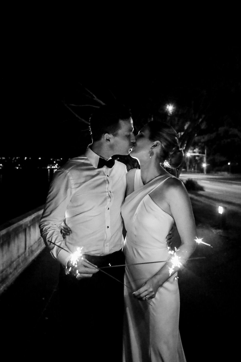 bride and groom kiss while holding sparklers for their exit