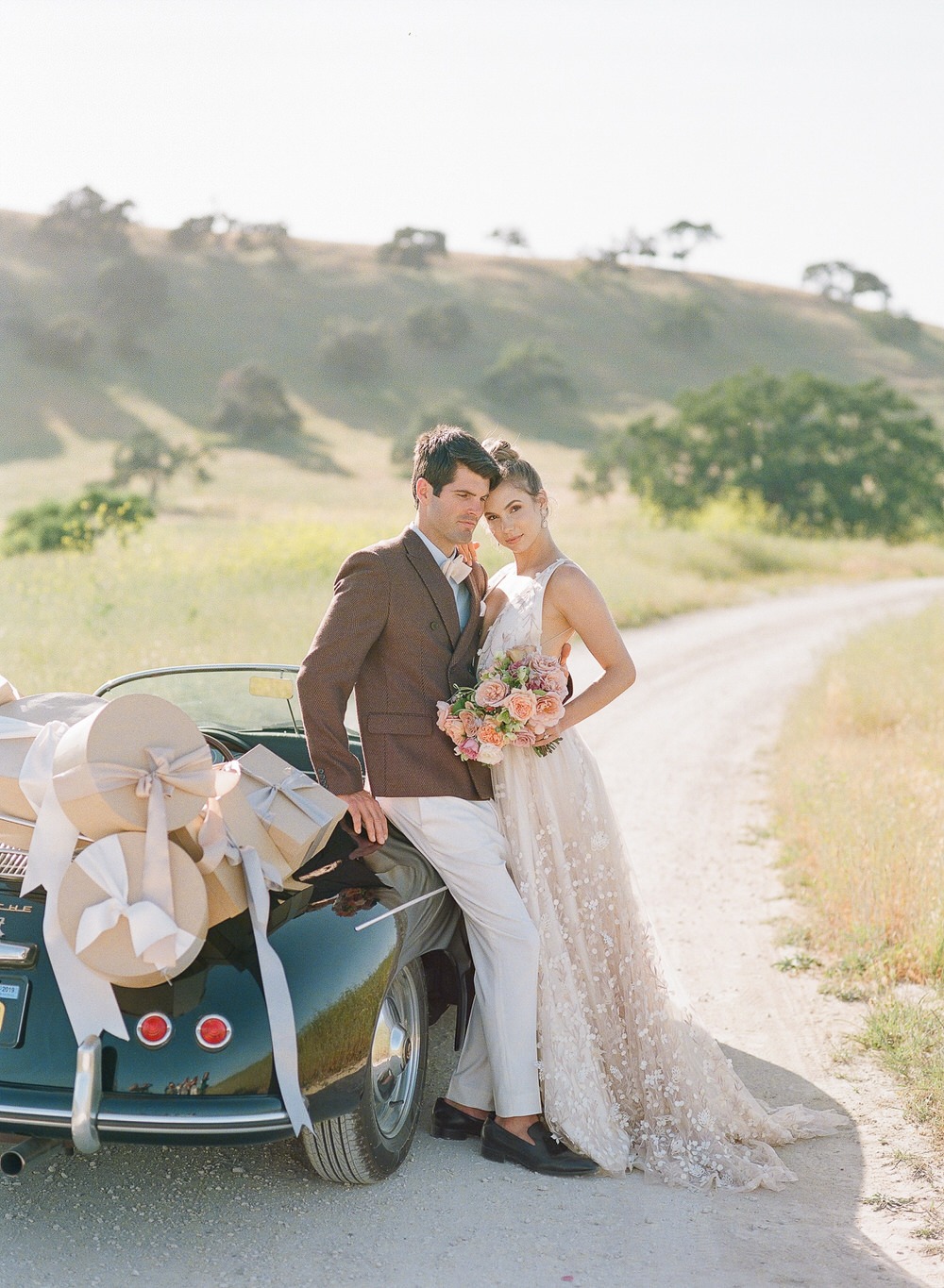 bride and groom standing next to their getaway car